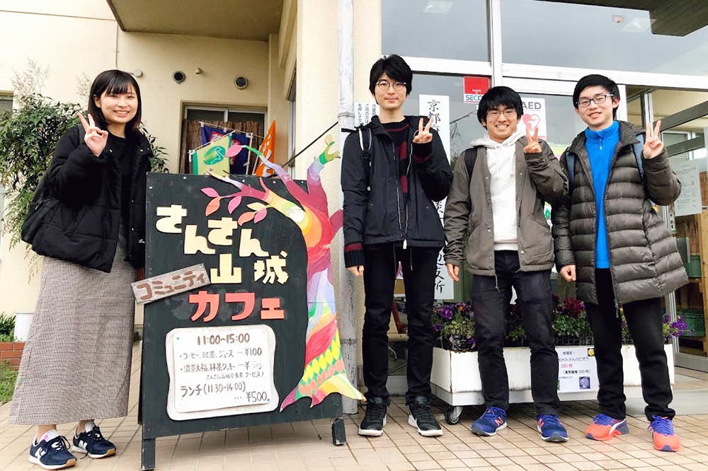 学生x社区连接未来项目的志愿者学生在京田边市三山社区咖啡馆前合影留念。金正日在最右边。